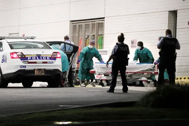 Penn Presbyterian Medical Center staff work to remove a patient from the police car that brought them to the hospital in July 2021. Presbyterian frequently treats patients brought to the hospital as part of the police's "scoop and run" policy and instituted new security procedures for patients brought in private cars after three nurses were injured in a hit-and-run at the hospital on Saturday.