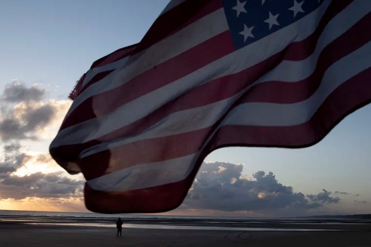 A man in a vintage US WWII uniform walks at sunrise prior to a D-Day 76th anniversary ceremony in Saint Laurent sur Mer, Normandy, France, Saturday, June 6, 2020. Due to coronavirus measures many ceremonies and memorials have been cancelled in the region with the exception of very small gatherings.