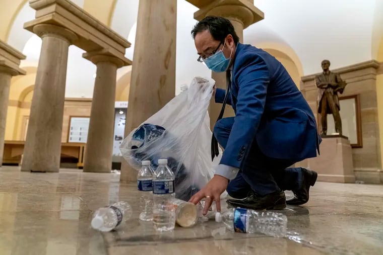 U.S. Rep. Andy Kim (D., N.J.) cleans up debris and trash strewn across the floor of the Capitol in the early morning hours of Jan. 7 after protesters stormed the building in Washington. Kim is now donating the blue suit he wore that day to the Smithsonian.