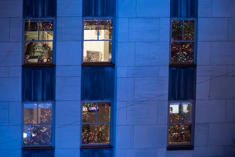 In this Nov. 28, 2018, file photo, people work in their office after the Rockefeller Center Christmas tree is lit during the 86th annual Rockefeller Center Christmas tree lighting ceremony in New York. Holiday staffing is one of a small business owner’s biggest stressors. But giving gifts or bonuses is a way for employees to feel valued.  (AP Photo/Mary Altaffer, File)