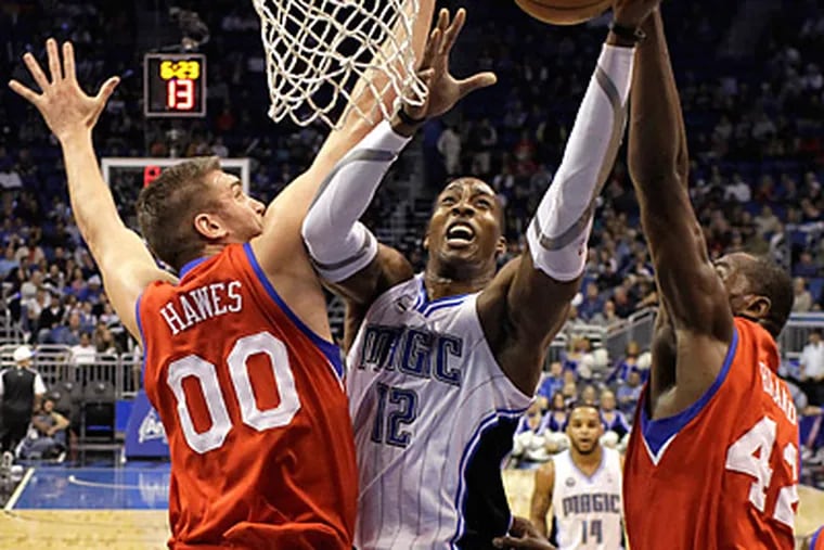 Orlando Magic center Dwight Howard tries to get a shot off between Spencer Hawes, left, and Elton Brand.  (AP Photo/John Raoux)