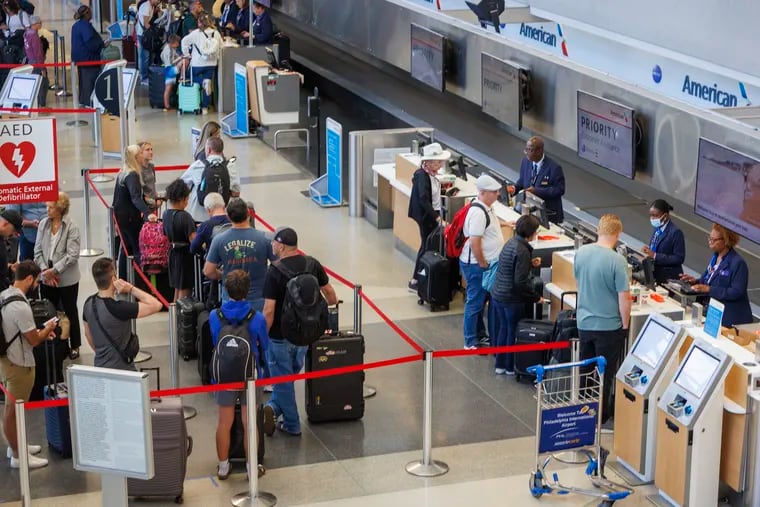 Travelers with American Airlines await agents at Priority Customer Assistance at Philadelphia International Airport Monday as passengers deal with flight delays and cancellations due to Tropical Storm Debby.