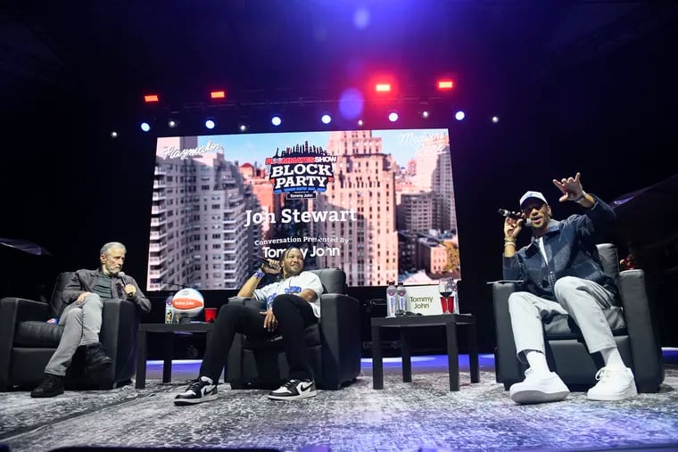 New York Knicks players Jalen Brunson, center, and Josh Hart, right, film the Roommates Live Podcast event in Central Park in New York. They are joined by Jon Stewart, left.