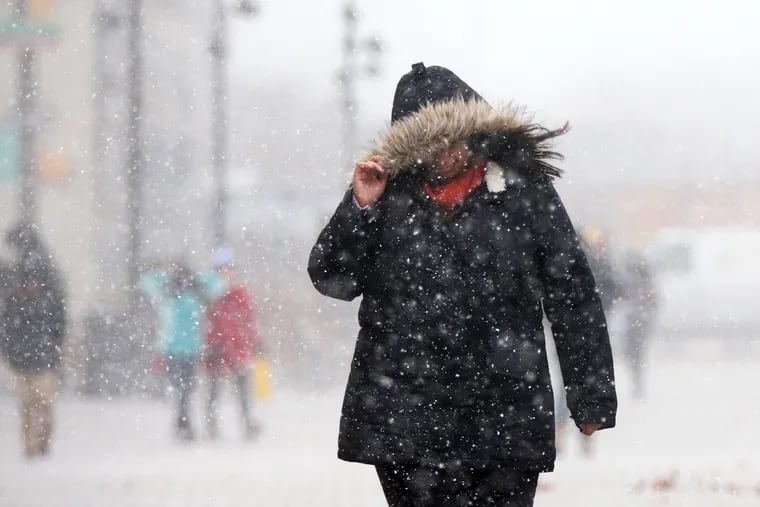 A pedestrian is caught in a snow squall on the campus of Drexel University in Philadelphia. The National Weather Service is forecasting temperatures to drop into the single digits overnight.