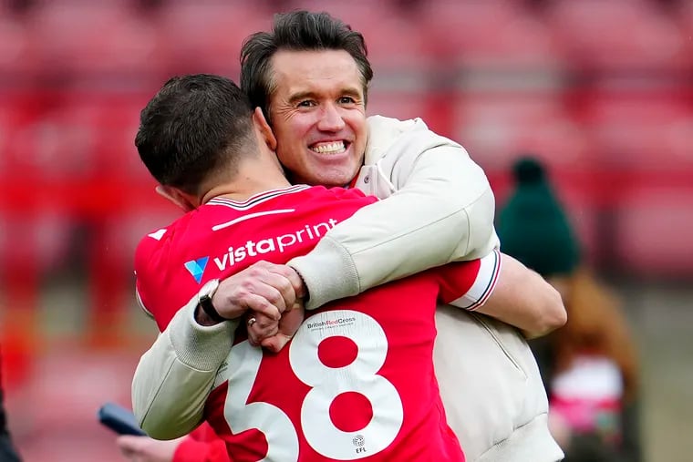 Wrexham Co-Owner Rob McElhenney, rear, and Elliot Lee of Wrexham celebrate after the English League Two soccer match between Wrexham and Stockport at the Racecourse Ground Stadium in Wrexham, Wales, Saturday, April 27, 2024. Wrexham AFC got promoted to League One.(AP Photo/Jon Super)