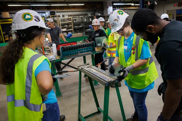 At right is sheet metal apprentice Najee Carter watching Ash bend sheet metal with a small bending Brake. Mentoring Young Women in Construction camp for girls at the Sheet Metal Training Center in Philadelphia, on Monday.