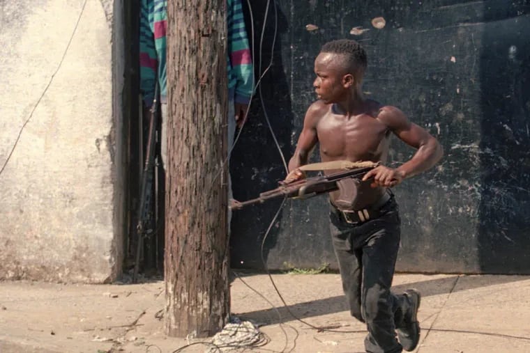 A teenage National Patriotic Front of Liberia (NPFL) fighter charges forward in downtown Monrovia, Liberia on May 10, 1996. 