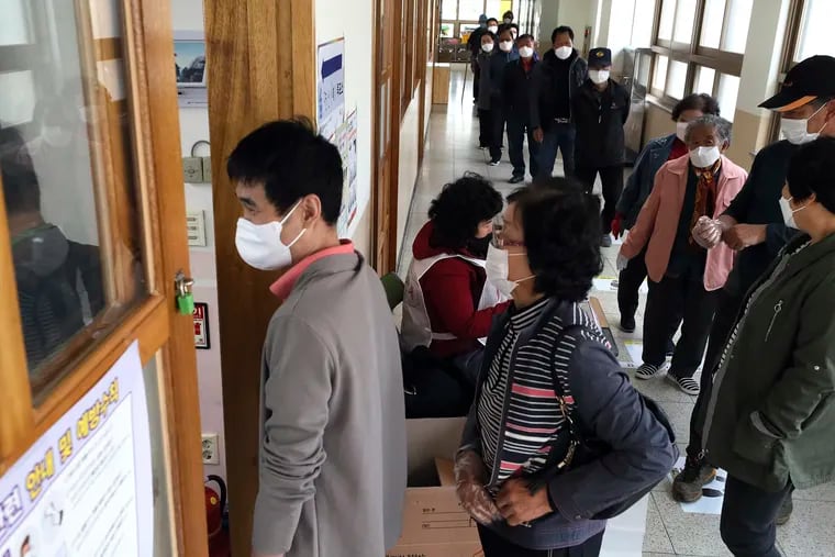People wearing face masks to help protect against the spread of the new coronavirus wait in line to cast for their votes for the parliamentary elections at a polling station in Nonsan, South Korea, Wednesday, April 15, 2020.