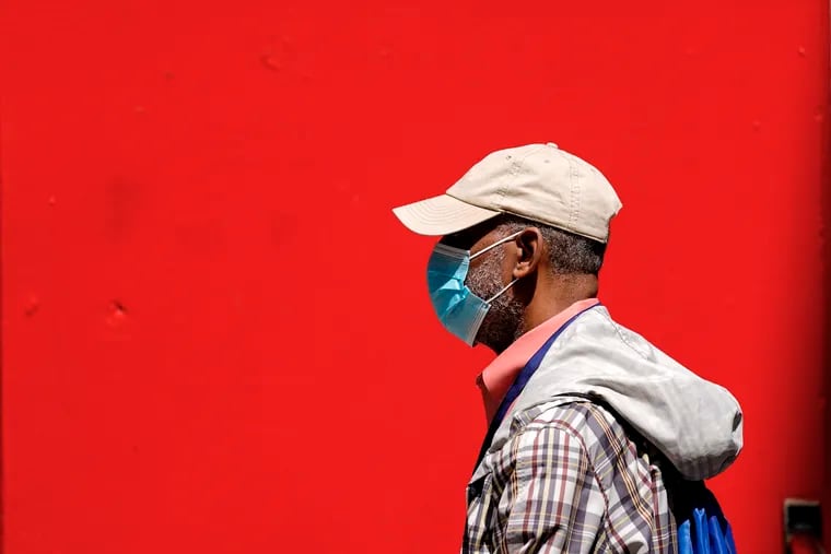 A pedestrian wearing a protective mask as a precaution against the spread of the coronavirus walks in Philadelphia, Friday, April 22, 2022.