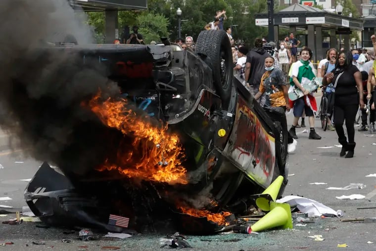 In this May 30 photo, protesters demonstrate as a Salt Lake City police vehicle burns.