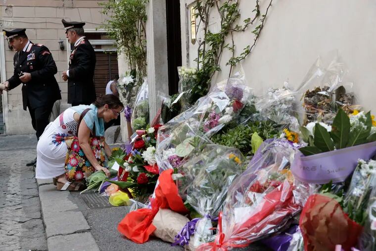 A woman leaves flowers in front of the Carabinieri station where Mario Cerciello Rega was based, in Rome, Saturday, July 27, 2019. In a statement Saturday, Carabinieri officers investigating the death Friday of officer Cerciello Rega, 35, said two American tourists, both 19, have been detained for alleged murder and attempted extortion.