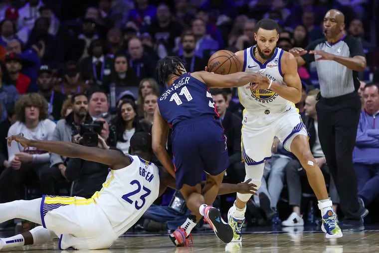 Golden State Warriors guard Stephen Curry and Philadelphia 76ers guard Jaden Springer battle for the ball while Golden State Warriors forward Draymond Green is called for a foul in the second quarter.