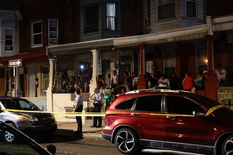 Neighbors watch from front porches as law enforcement investigate a shooting involving a Philadelphia police officer at G and Schiller Streets in Philadelphia on Saturday.