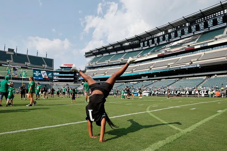 Eagles fan Taylor Hill, 7, of Dover, Del., performs a cart wheel before the start of the Eagles team open practice at Lincoln Financial Field on Thursday, Aug. 1, 2024.