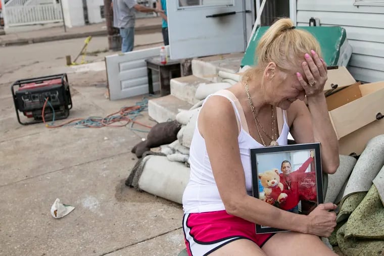 Laura Sinnott Caroluzzi tears up while she holds a photo of her husband, Jack Caroluzzi, who died in Wednesday evening’s flooding, outside of their home in Bridgeport, Pa.