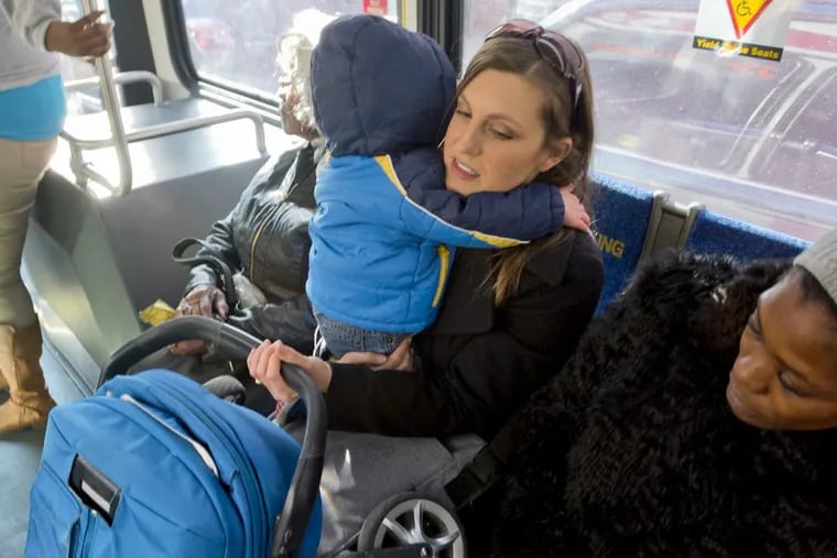November 10, 2017 — Lacey Kohlmoos holds her 1-year-old son Finn Heckert and their folded up stroller while riding the bus. Kohlmoos has started a petition to ask SEPTA to allow parents to bring their strollers onto the bus unfolded. (Avi Steinhardt/ For the Philadelphia Inquirer)