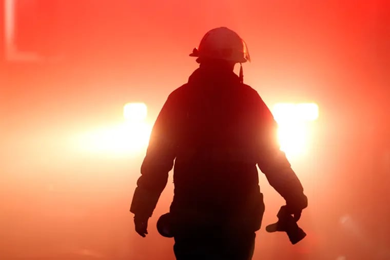 A firefighter walks through smoke from a fire Monday, Dec. 10, 2012, in Philadelphia. Fire Department Executive Chief Richard Davison says the blaze broke out Monday afternoon at a three-story industrial garage. Davison says an elderly woman has been taken to the hospital in stable condition. The woman's injuries were not immediately clear. (AP Photo/Matt Rourke)