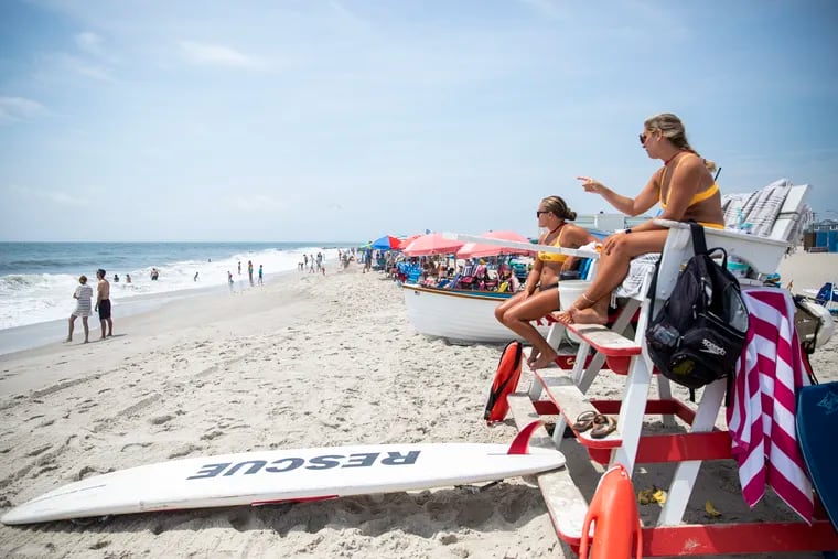 Lifeguards Megan O’Malley (right) and Sara Jackson keep watch as people enjoy the surf at Cape May, N.J., in 2022.