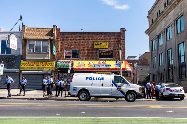 Philadelphia Police Officers grouped up along the sidewalk in front of store in Kensington in June.