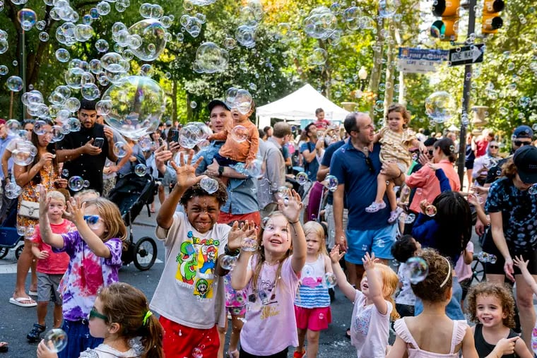 Youngsters enjoy soap bubbles created by Matthew Sconzo with George the Magician during the city's Open Streets program.