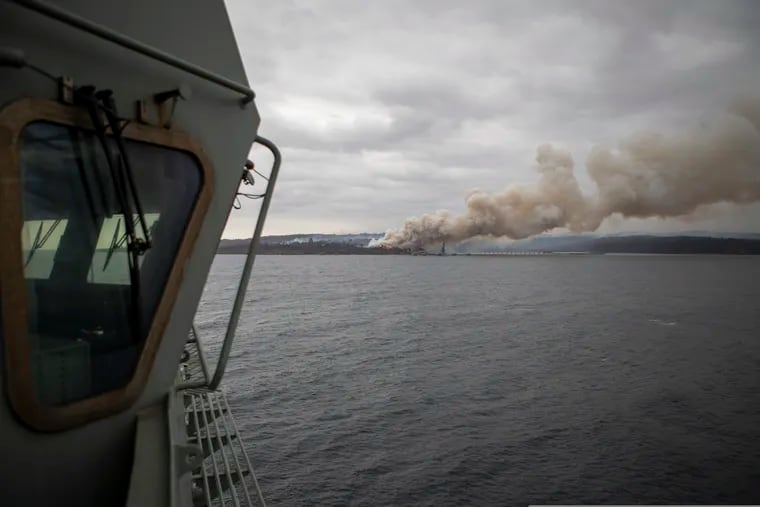 In this photo provided by the Australian Department of Defence on Jan. 6, 2020, a fire burns near Eden as HMAS Adelaide arrives to assist with wildfires. The wildfires have so far scorched an area twice the size of the U.S. state of Maryland. They have destroyed about 2,000 homes.