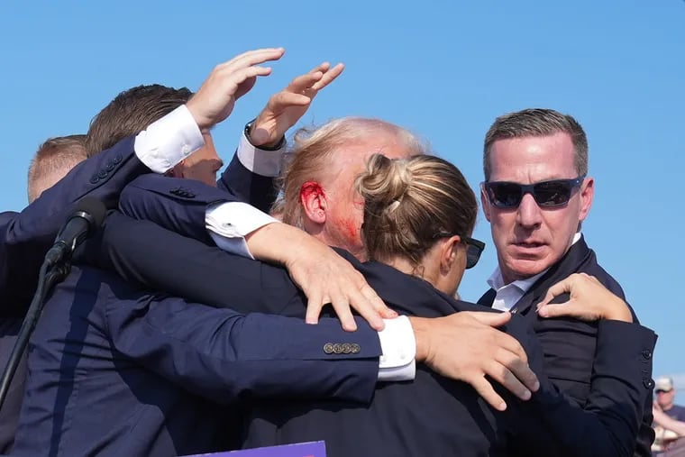 Blood appears on the ear of former president Donald Trump as he is assisted offstage during a campaign rally in Butler on July 13.