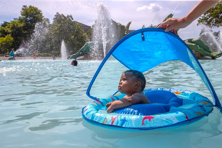 Tamir Washigton, 6 months to the day, tries out his new floating device with the guiding hand of his mother, Laura Morrone, at the fountains at Logan Circle on Wednesday.