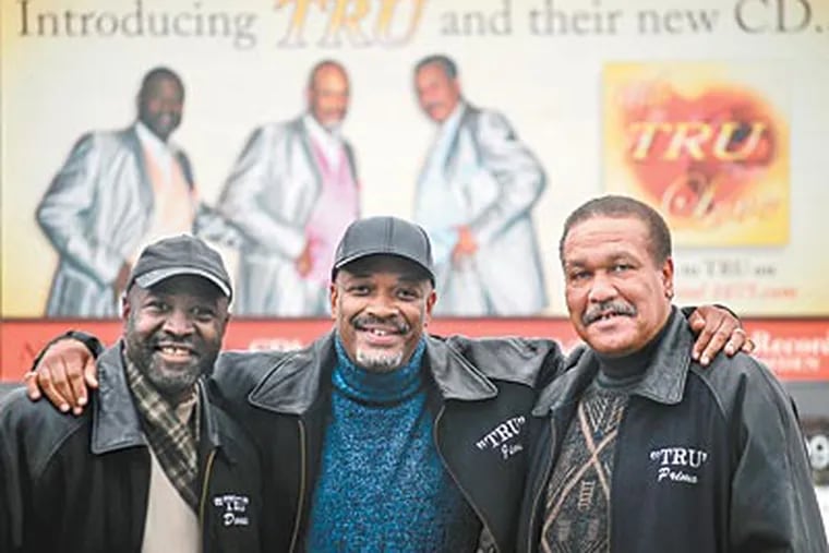 Members of the soul singing group TRU from left to right, LaVon "Donnie" Tatem, Jimi "Jai" Williams, and Primo Wesley stand near a billboard promoting TRU's first new album, "With TRU Love." ( Sarah Schu / Staff Photographer )