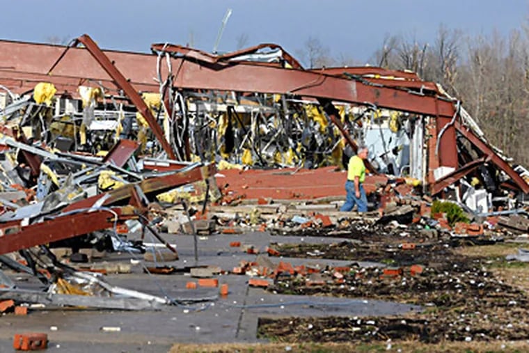 An employee of Henryville High School in southern Indiana examines the storm-blasted rubble of the building. Forecasters said the massive storm system had put 10 million people at high risk. (Timothy D. Easley / Associated Press)