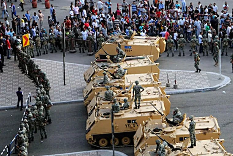 Military vehicles block the road outside the Defense Ministry in Cairo as troops attempt to stand their ground against protesters. Despite official warnings against gathering, groups that had been demonstrating in Tahrir Square converged on the area. AHMED HAMMAD / Associated Press