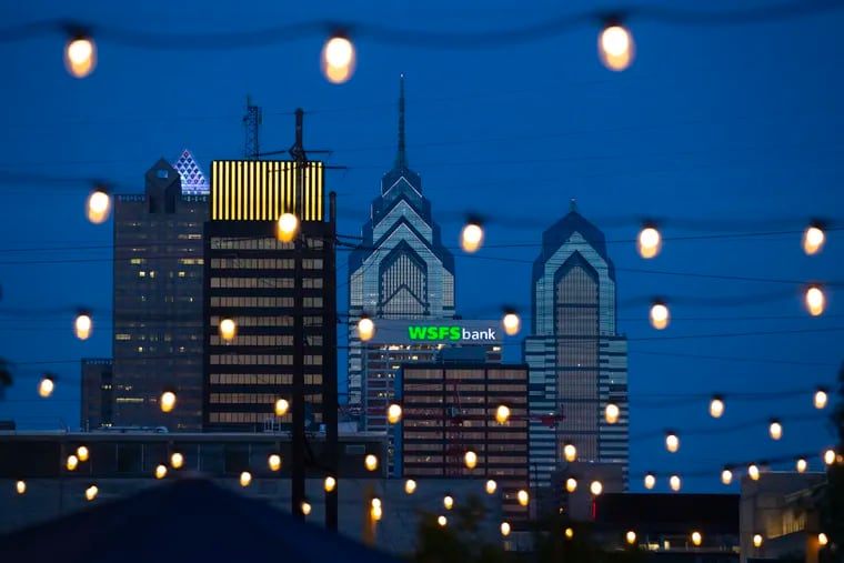 The Peco building is lit yellow at its top as part of the Philadelphia skyline, seen through Gateway Garden on the campus of Drexel University.