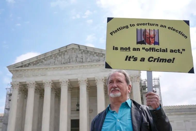 A demonstrator stands outside the U.S. Supreme Court Building as justices prepared to hear arguments in April over whether Donald Trump is immune from prosecution in a case charging him with plotting to overturn the results of the 2020 presidential election.