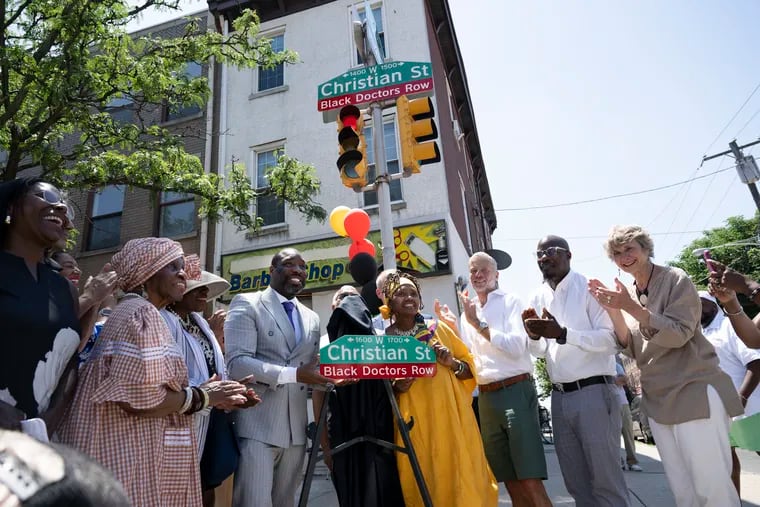 City Council President Kenyatta Johnson and Linda Evans, a board member of the South of South Neighborhood Association, display a street sign dedicating a stretch of Christian Street as Black Doctors Row on June 21.