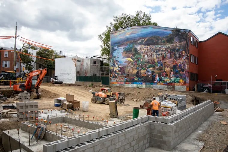 Ann Northrup, 71, a Philadelphia artist, painted the "One World" mural next to the Independence Charter School playground nearly a decade ago. Now, a charter school expansion threatens to obstruct the mural. Northrup is using high-resolution photography to recreate the piece so it can be moved elsewhere.