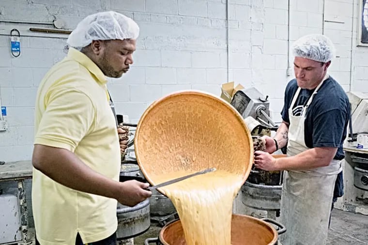 With wooden paddles and copper vats, workers at Stutz make candy the old-fashioned way. Workers Kerwin Subero (left) and Sean Shanahan transfer a batch of fudge for the next stage in the process. (ED HILLE/Staff Photographer)