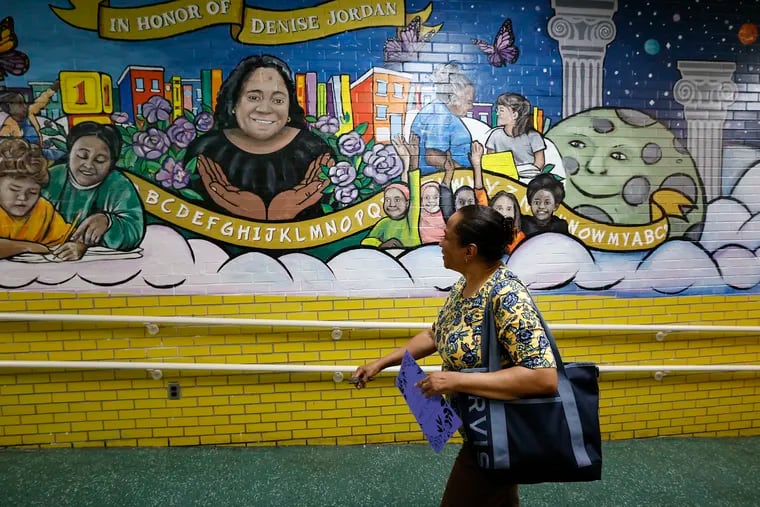 Asuncion Walters looks at the mural of her sister, Denise Jordan, a longtime kindergarten teacher at John Barry Elementary School in West Philadelphia during a kindergarten mural dedication and ceremony on Thursday.  Jordan died suddenly at age 53 last summer.