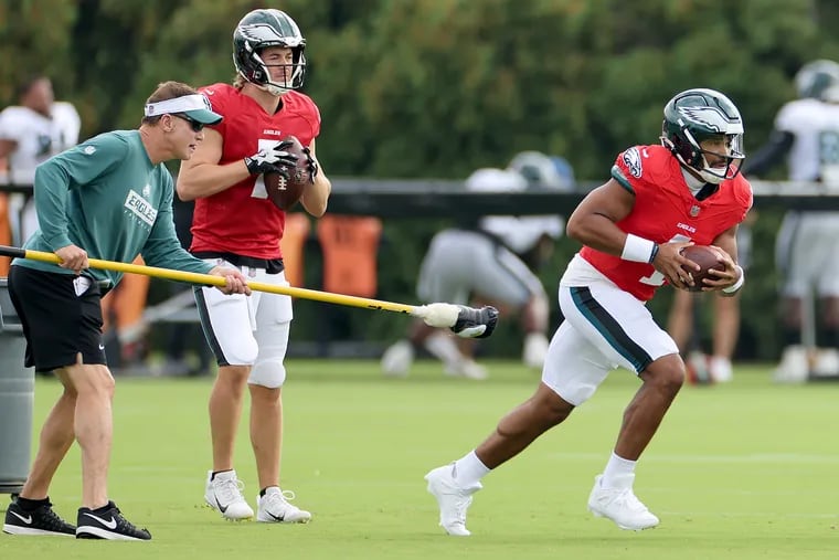 Jalen Hurts (right) runs during a ball-protection drill earlier in Eagles training camp.