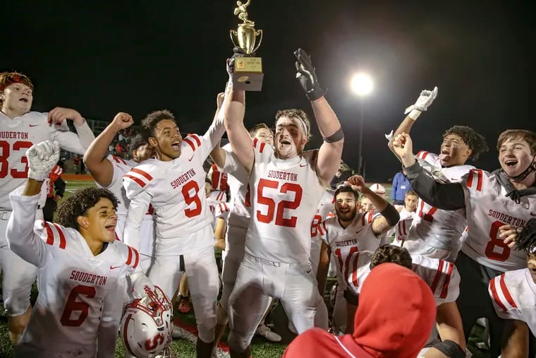 Souderton's Aonghas Evanick (52) holds the championship trophy after the Big Red beat Pennridge for the PIAA District 1 Class 6A Championship Friday.