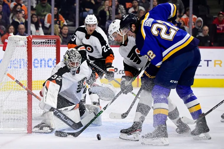 Flyers goaltender Felix Sandström, right, makes a save as Justin Braun and the St. Louis Blues' Logan Brown (22) battle for the puck during the first period on Tuesday in Philadelphia. Sandström earned his first win in nine NHL starts.