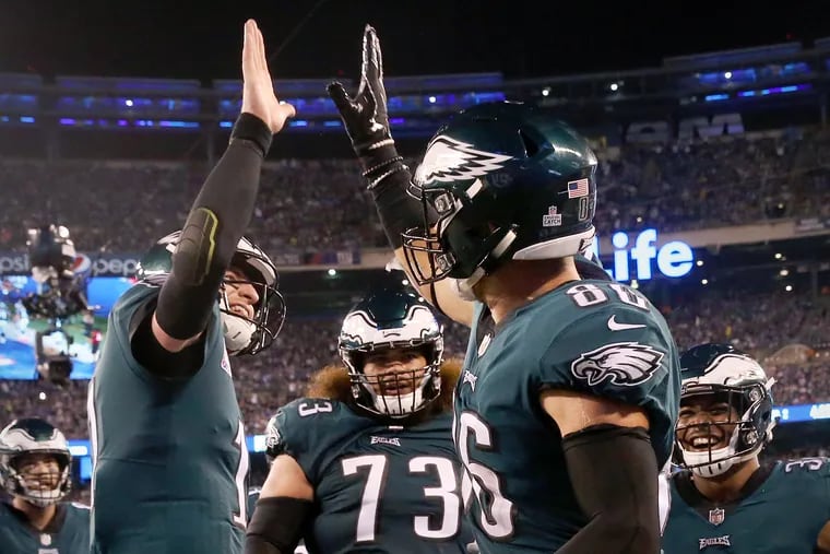 Eagles quarterback Carson Wentz (11) high-fives tight end Zach Ertz (86) after Ertz scored a touchdown in the second quarter of a game against the New York Giants at MetLife Stadium in East Rutherford, N.J., on Thursday, Oct. 11.