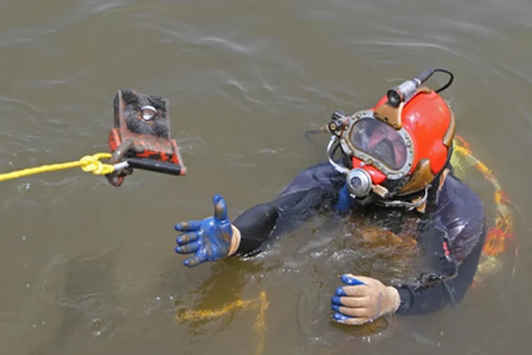 Andrew Yoder reaches for a magnet to bring up more debris from the Delaware. (Michael Bryant / Staff Photographer)