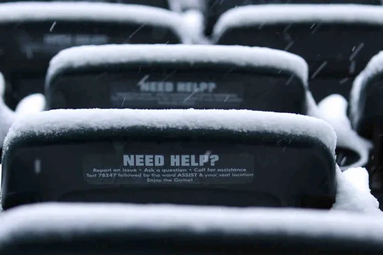 Snow falls on Lincoln Financial Field seats with &quot;need help&quot; signs.
