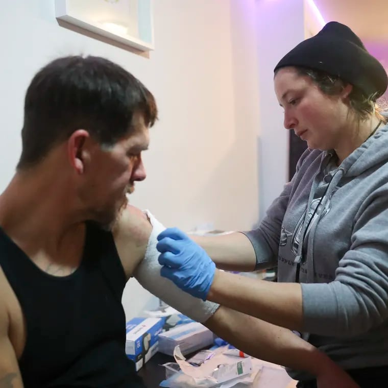 Jen Shinefeld, a Field Epidemiologist, cleans the wound on the arm of Nick Gallagher at Savage Sisters, an outreach organization based in Kensington, in Philadelphia on Tuesday, Jan. 10, 2023. The staff at Savage Sisters help treat xylazine wounds and help people through withdrawal.