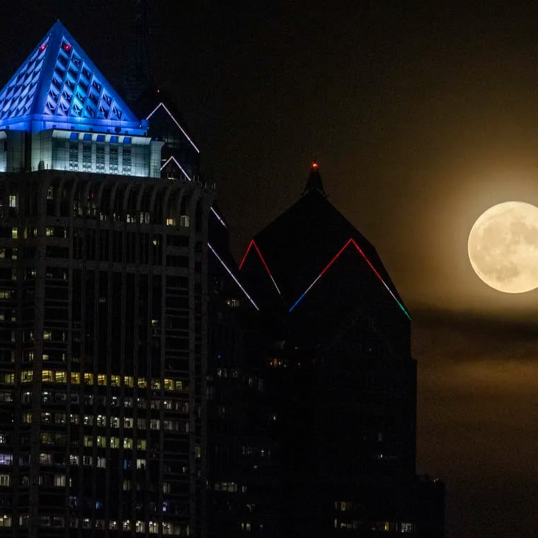 The supermoon rises over part of the city skyline on July 13, 2022.