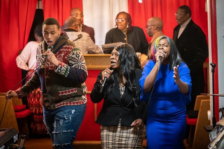 Rachel Turner (center) sings at God’s Deliverance Church in Philadelphia on Sunday, three days after her son Isaiah Odom was shot and killed. Odom’s brother (left) and his sister Dawinea Lyons (right) sing along with Turner.