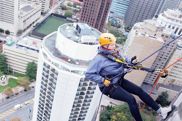 Outward Bound director Katie Newsom Pastuszek begins to rappel down 31 stories at One Logan Square during the two-day fundraiser for the Philadelphia Outward Bound School. MACKENZIE FOX / For The Inquirer