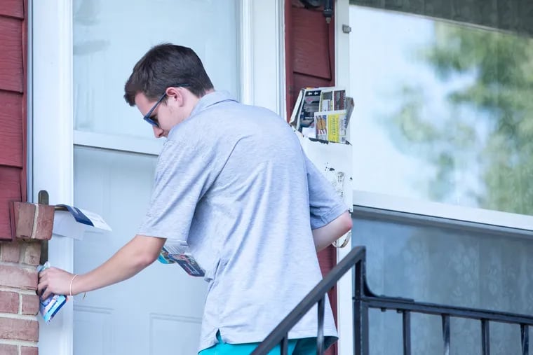 Seth Matson, 26, places campaign literature at a door in Lower Allen Township last month. Matson is a field organizer for Democratic state House candidate Sara Agerton.