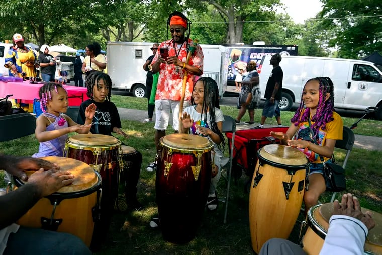 Diverse Conscious of Parkside, known as “Moses” to those who see him walking all over the city with his walking stick, stops for his children to play with drummers while celebrating Father's Day during the Camden Juneteenth Weekend Celebration at Farnham Park, Sunday, June 18, 2023. His kids (from left) Nandi, 5; Infinite, 8; Oma, 10; and Supremaa,11. Conscious, a single dad, has a fifth child, Supreme, 13, who was helping a friend at his vendor’s booth. Conscious was gifted the stick by the wife of his mentor, after the mentor's death. The Juneteenth event featured live entertainment, vendors, and food.