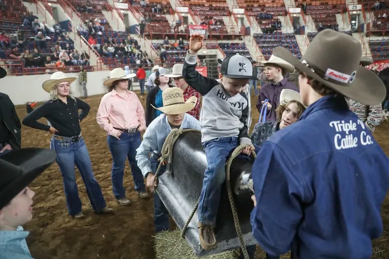 Kai Konopinski, 4, is lifted up by High School Rodeo competitors as he pretends to ride a bull during the High School Rodeo Meet and Greet at New Holland Arena on the first day of the Pennsylvania Farm Show in Harrisburg, Pa. on Saturday, Jan. 7, 2023.