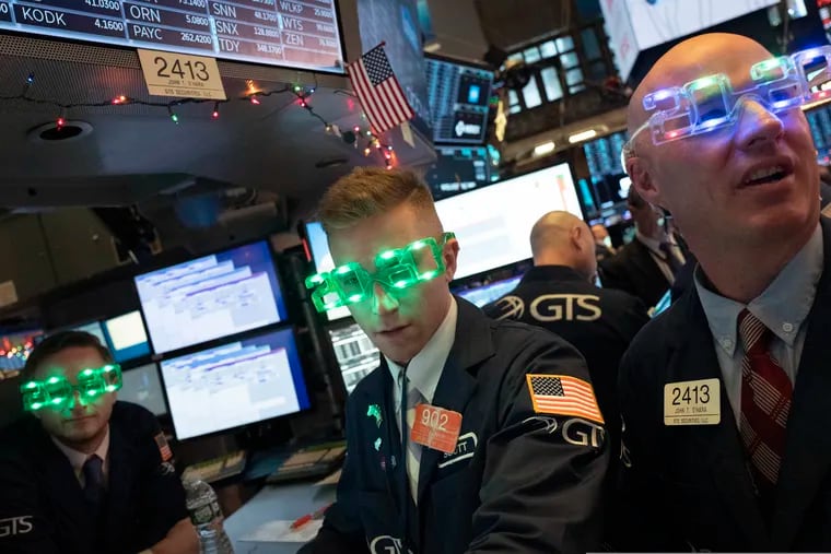 Stock traders wear New Year's 2020 party glasses at the New York Stock Exchange, Tuesday, Dec. 31, 2019. Stocks slipped globally in quiet New Year's Eve trading Tuesday with many markets closed. Wall Street could close 2019 with back-to-back daily losses in a year that the U.S. posted the largest market gains since 2013.